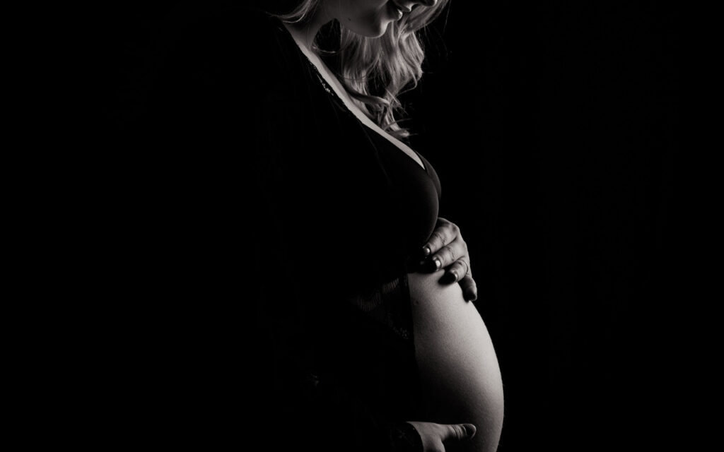 Mulher grávida com a mão na barriga pensando em pensao alimenticia